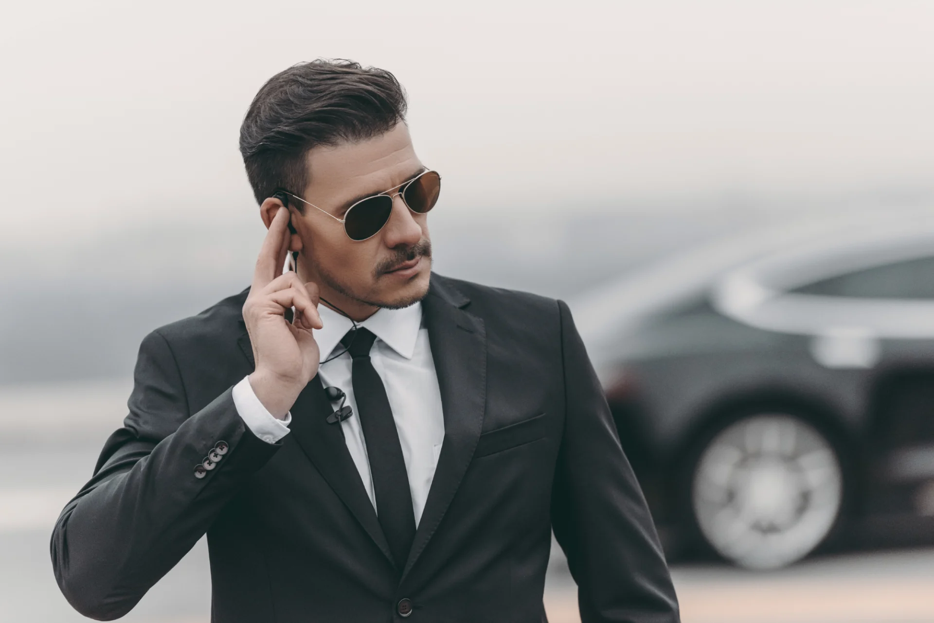 A man in suit and sunglasses talking on his cell phone.