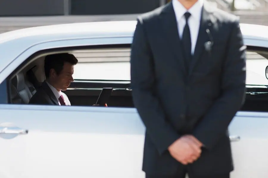 A man in suit and tie standing next to a car.