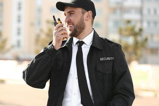 A man in black jacket holding a walkie talkie.